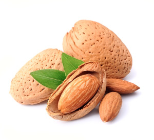 Almonds nuts with leaves close up on white background .